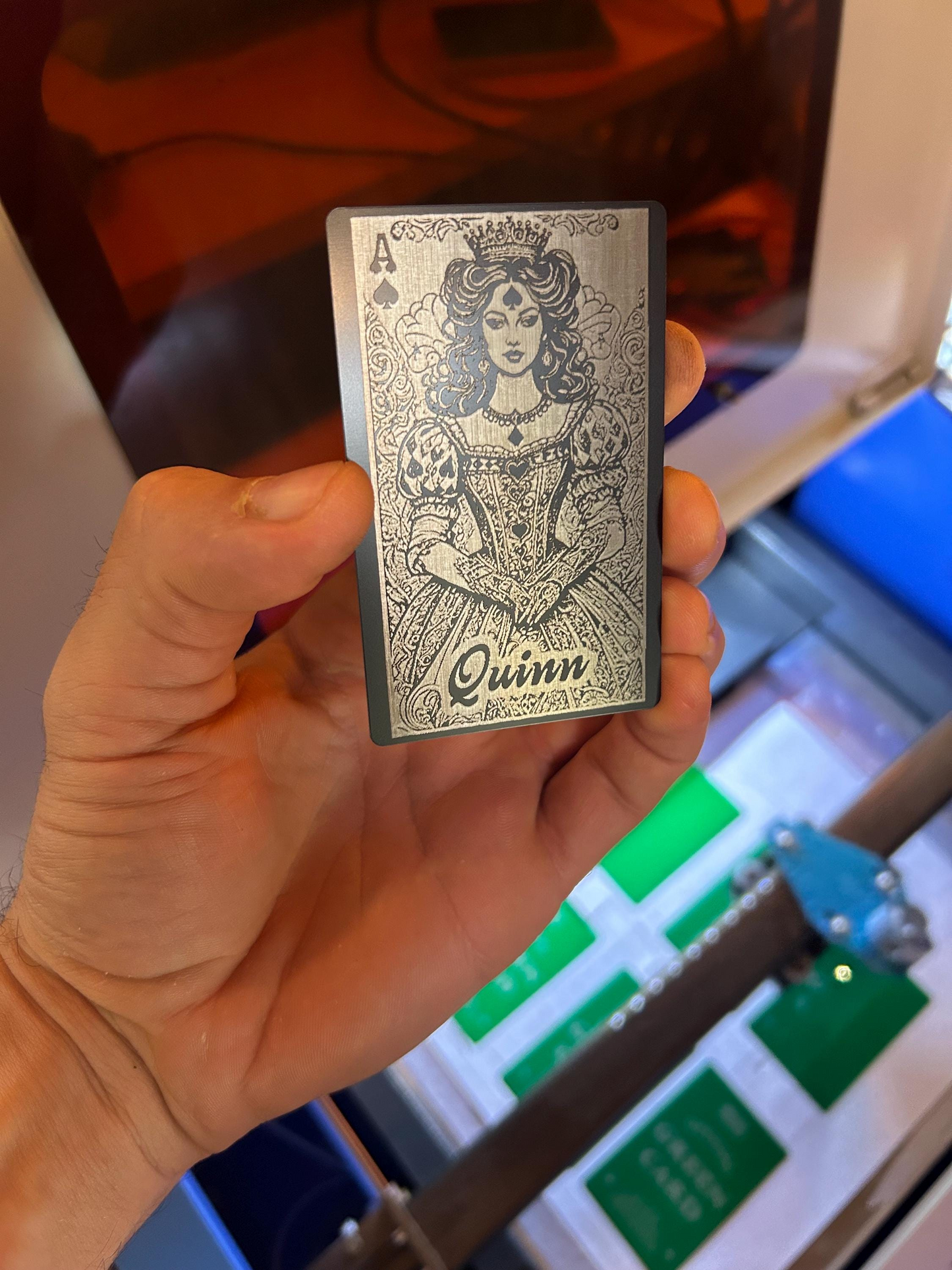 Person holding engraved aluminum Ace of Spades card – Lady Luck design in black and silver metal finish with personalized name "Quinn"