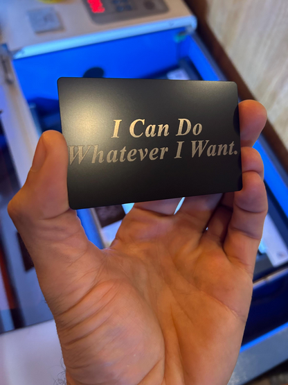Hand holding a black laser engraved card with 'I Can Do Whatever I Want' text.
