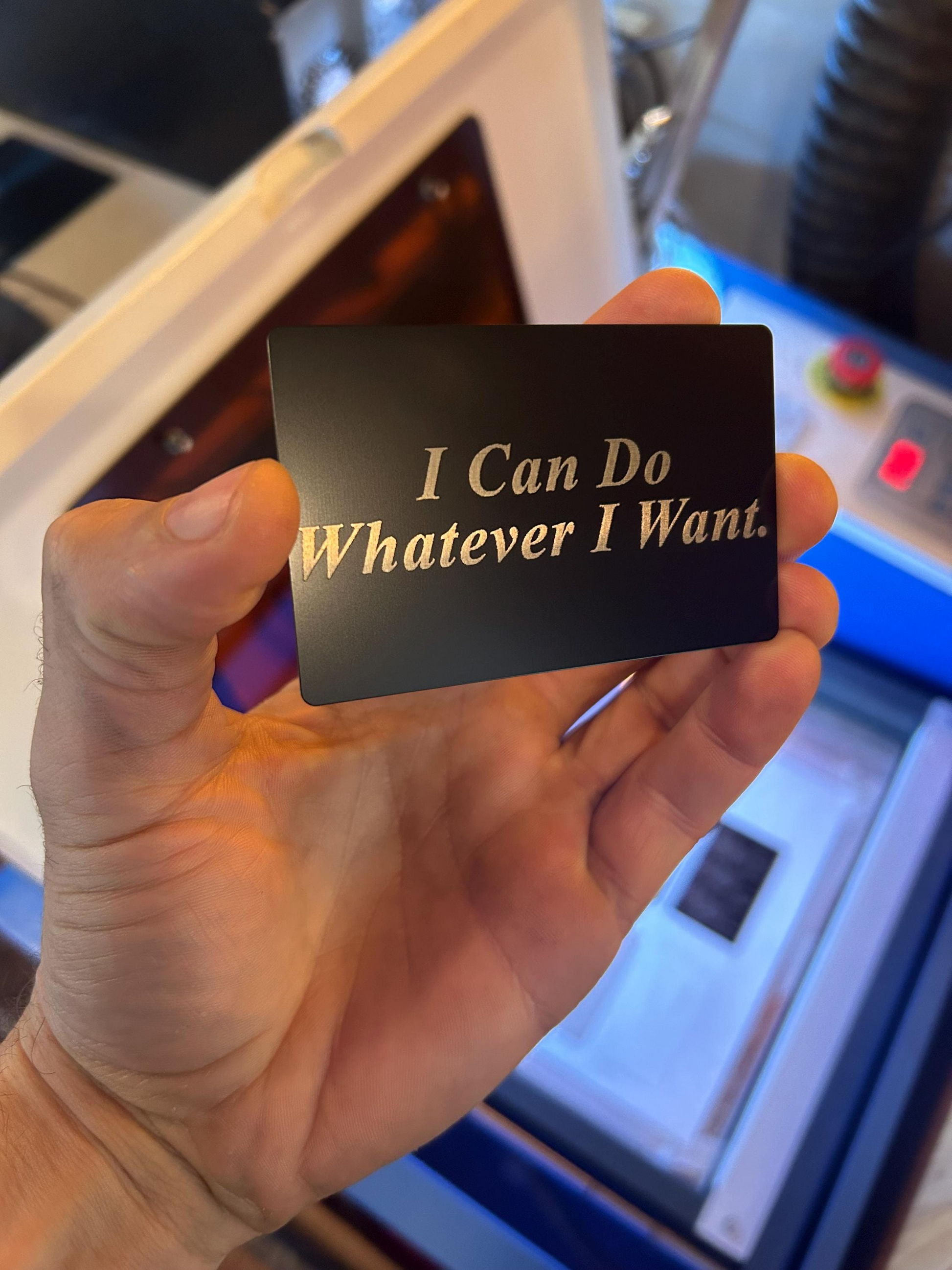 Hand holding a black card with 'I Can Do Whatever I Want' text in silver.