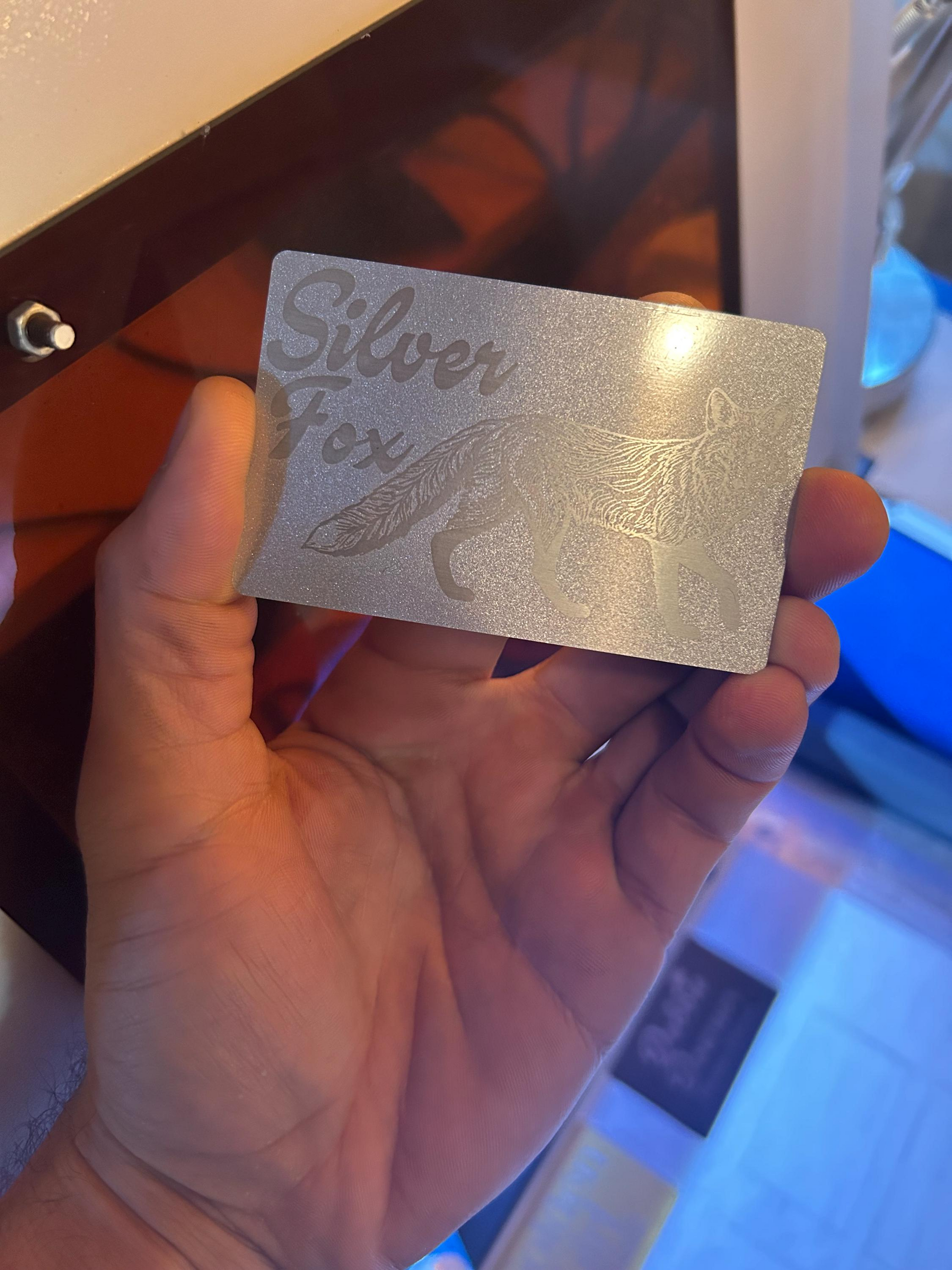 Hand holding a silver metal novelty gift card with 'Silver Fox' text and graphic.