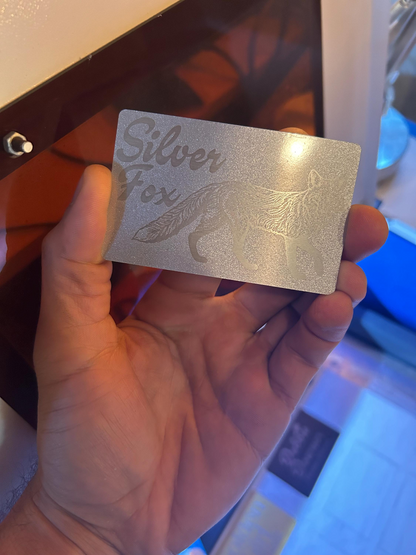 Hand holding a silver metal novelty gift card with 'Silver Fox' text and graphic.