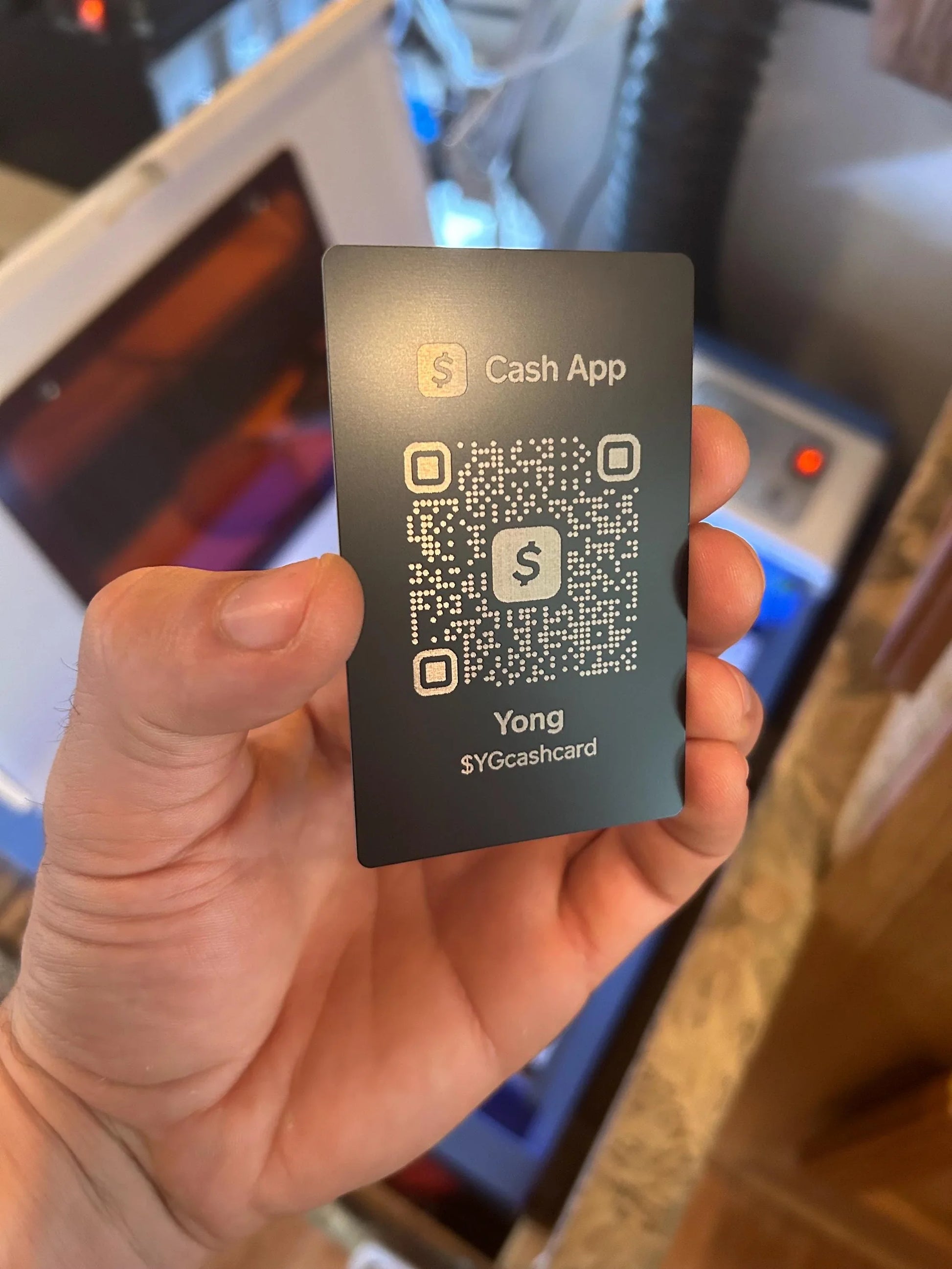 Hand holding a Cash App card with a QR code and logo.