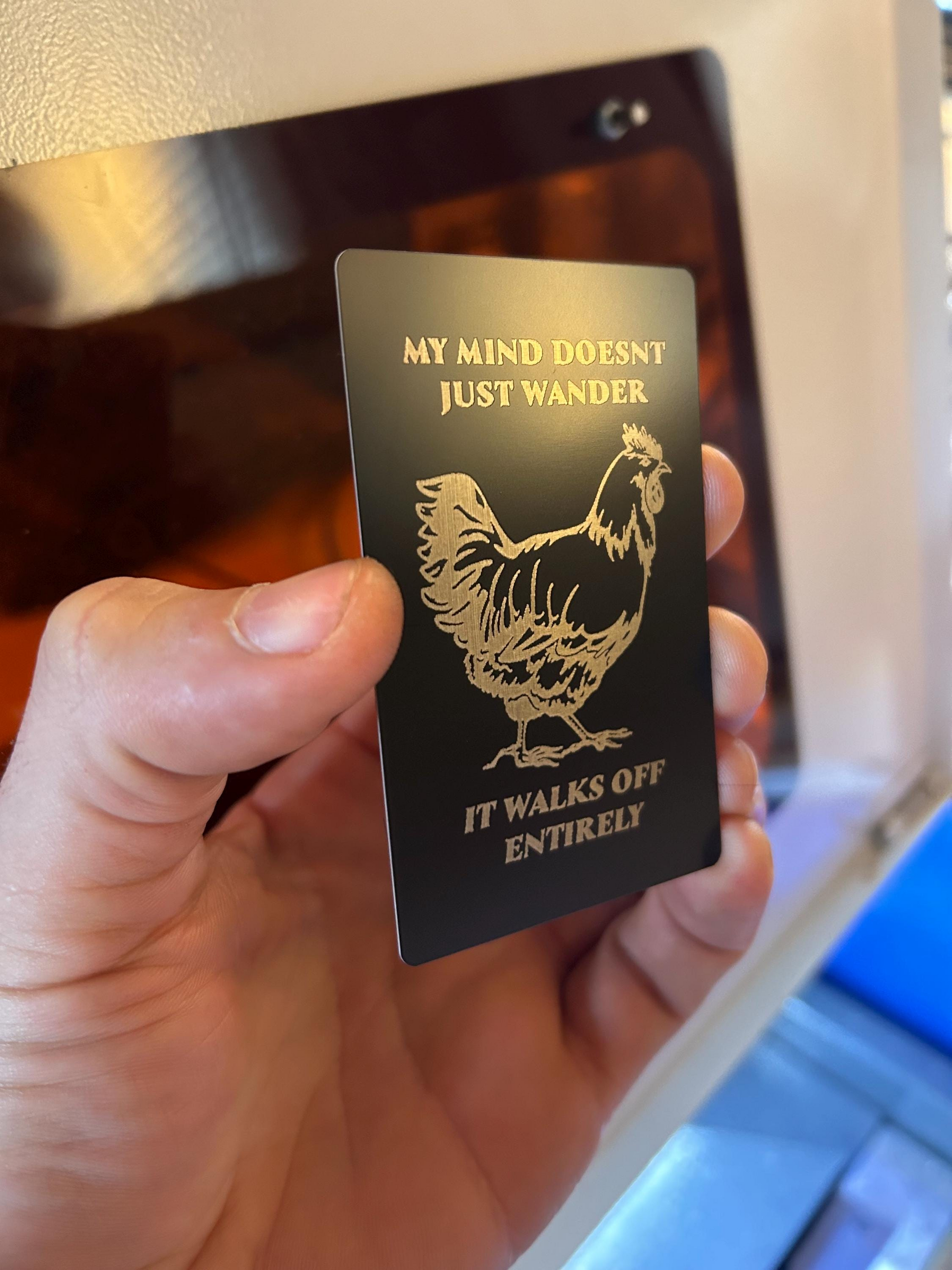 Person holding a funny farmhouse gift card engraved with chicken graphic and humorous wandering mind text