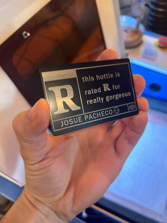 Hand holding a small metal sign with text and a letter 'R' on it and customized name engraving
