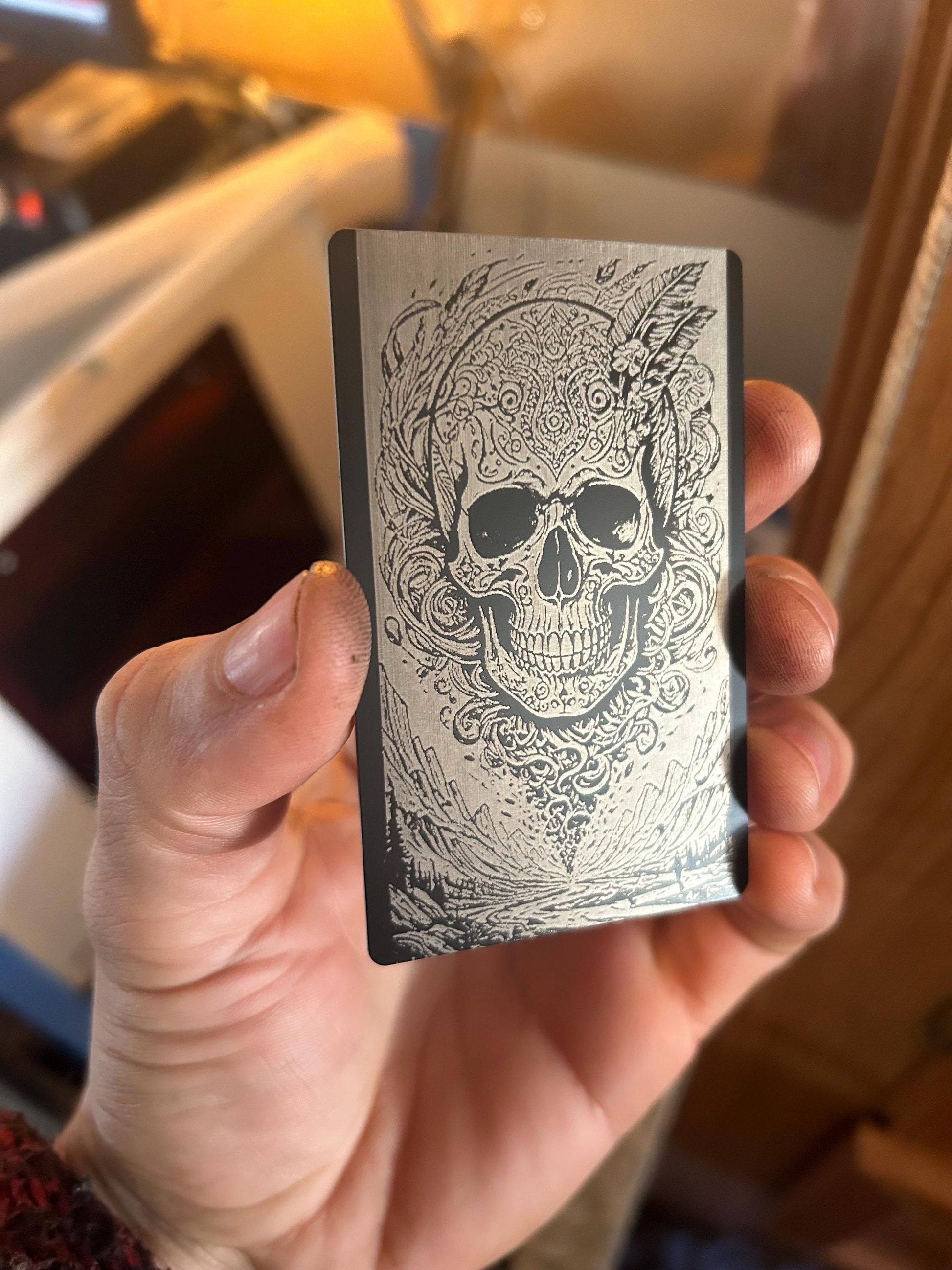 Hand holding a deck o metalf cards with a skull design against a blurred background
