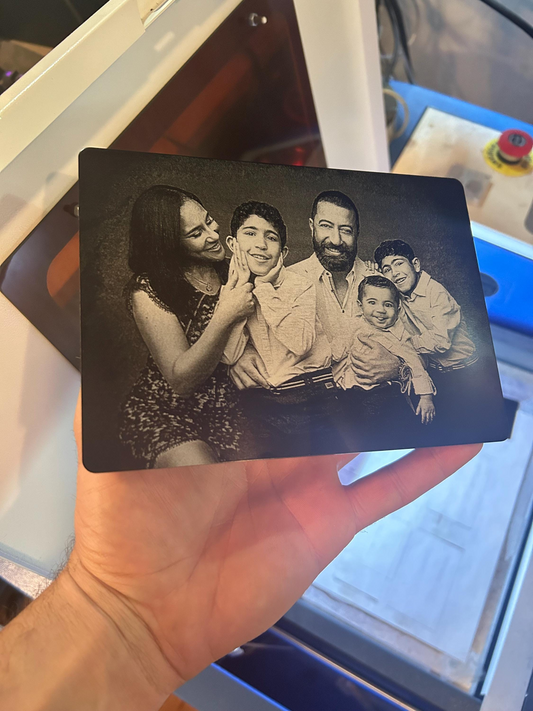hand holding Laser engraved 7x5" metal plaque photo of family in front of blurred machine