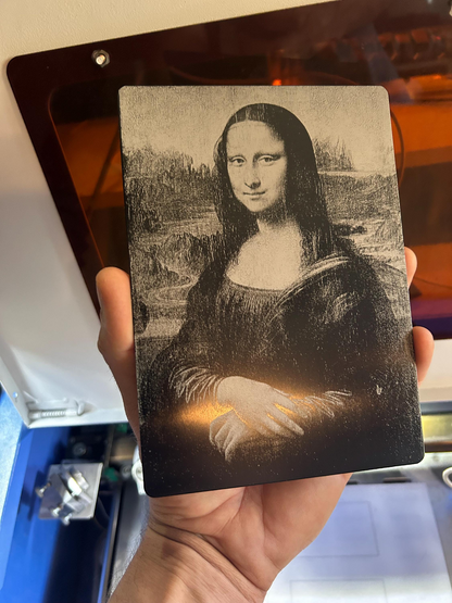 Hand holding metal laser engraved plaque with highly detailed painting Mona Lisa laser engraved design