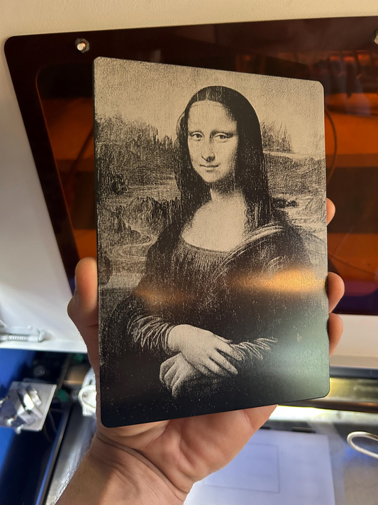 Hand holding a 5x7 anodized aluminum decorative plaque with highly detailed laser engraving of The Mona Lisa 