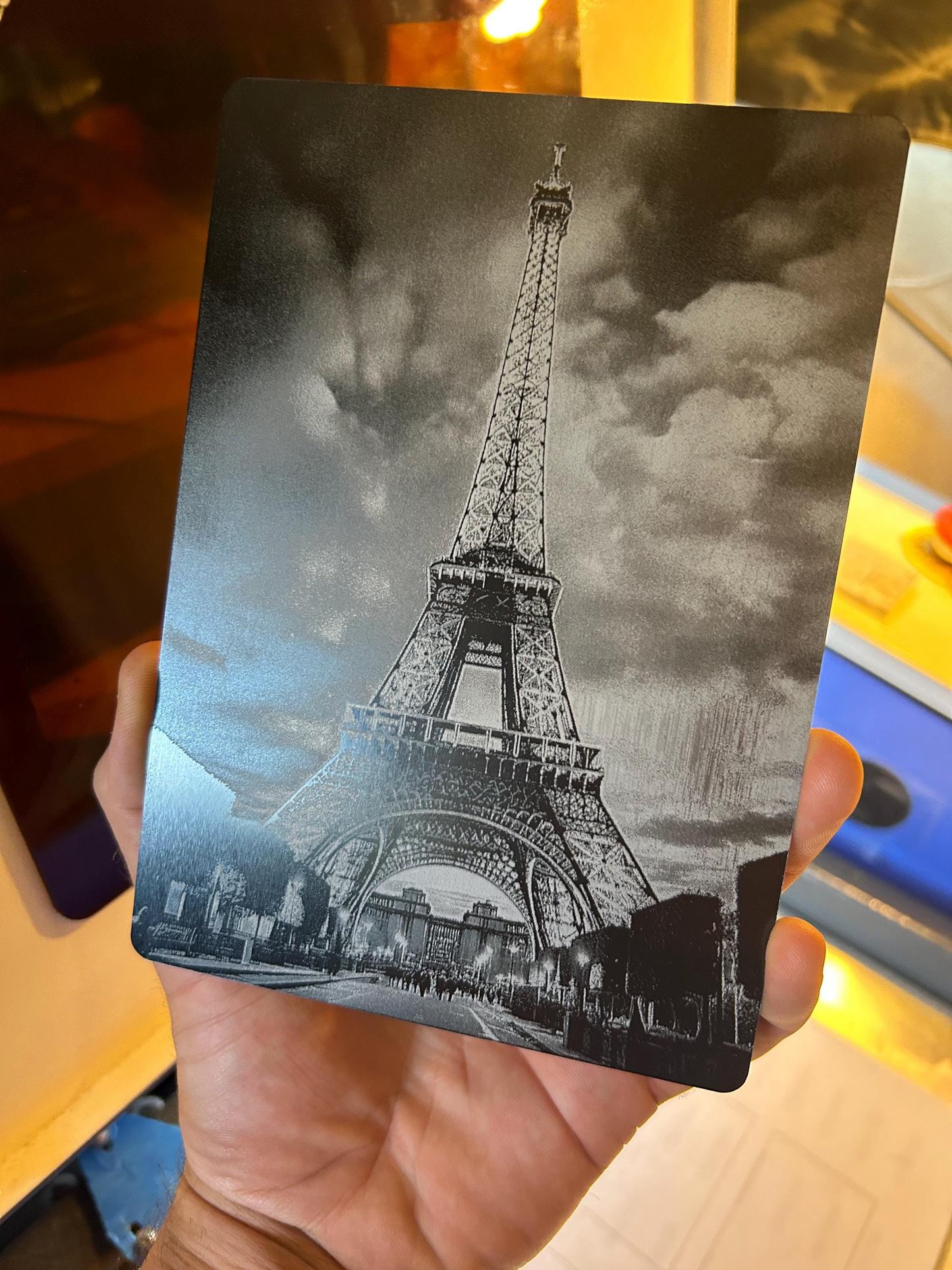 hand holding a metal laser engraved 5x7" eiffel tower world wonder landmark on matte black anodized aluminum
