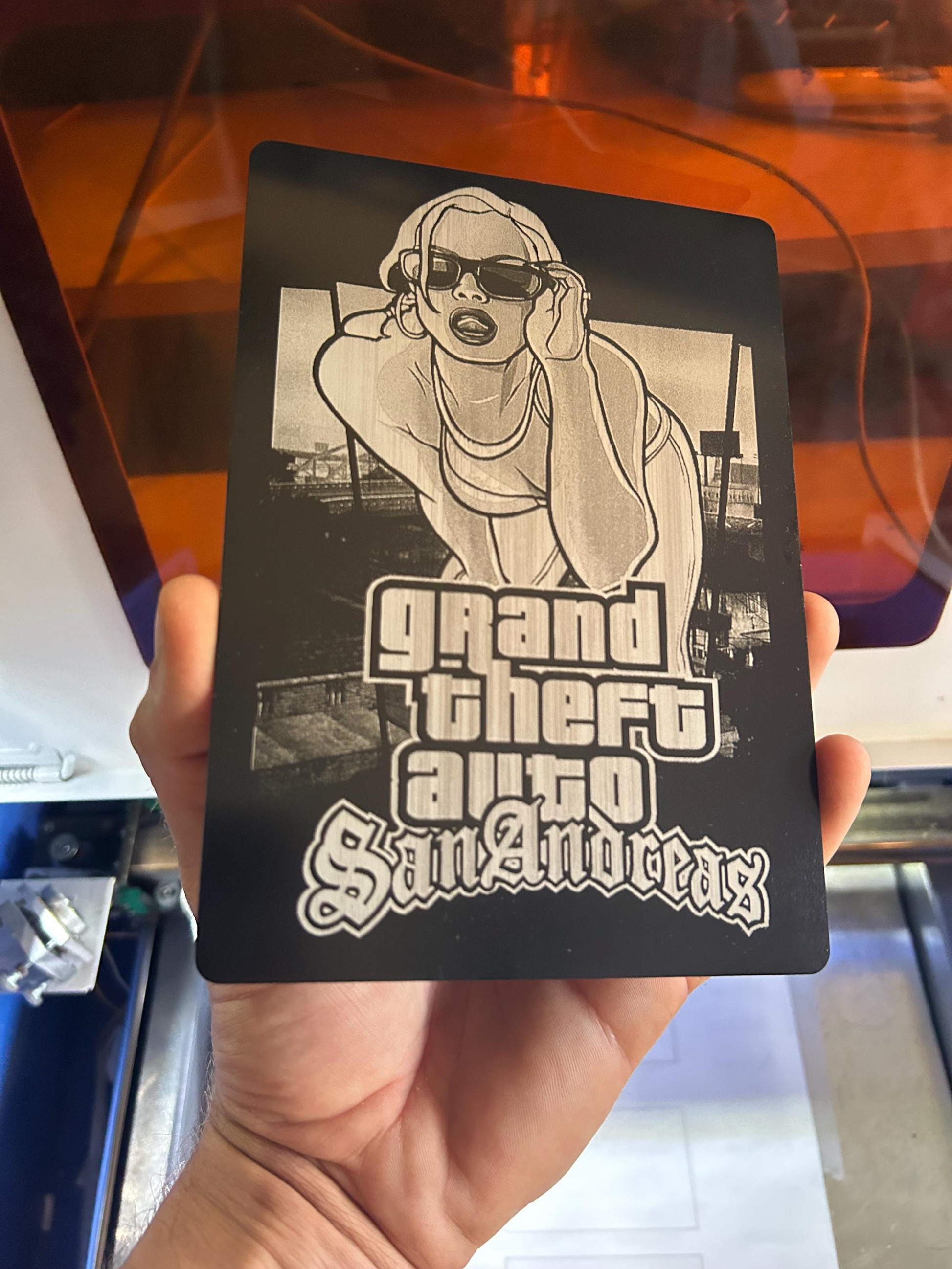 Hand holding laser engraved video game box artwork fan art engraving on 5x7 black/silver anodized aluminum