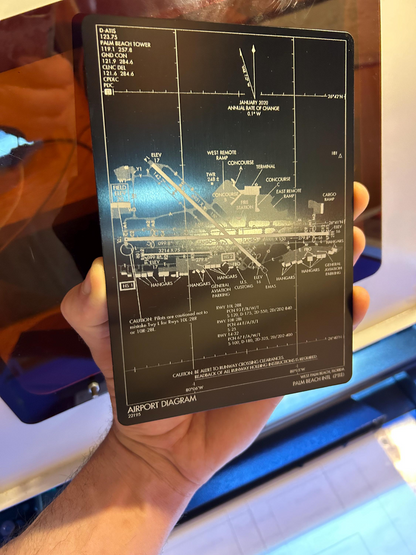 Hand holding a black 5x7 plaque with an airport diagram