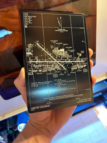 Hand holding an airport diagram card with detailed layout laser engraved on anodized aluminum plaque