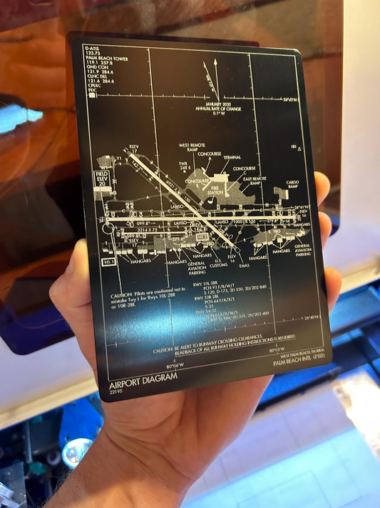 Hand holding an airport diagram card with detailed layout laser engraved on anodized aluminum plaque