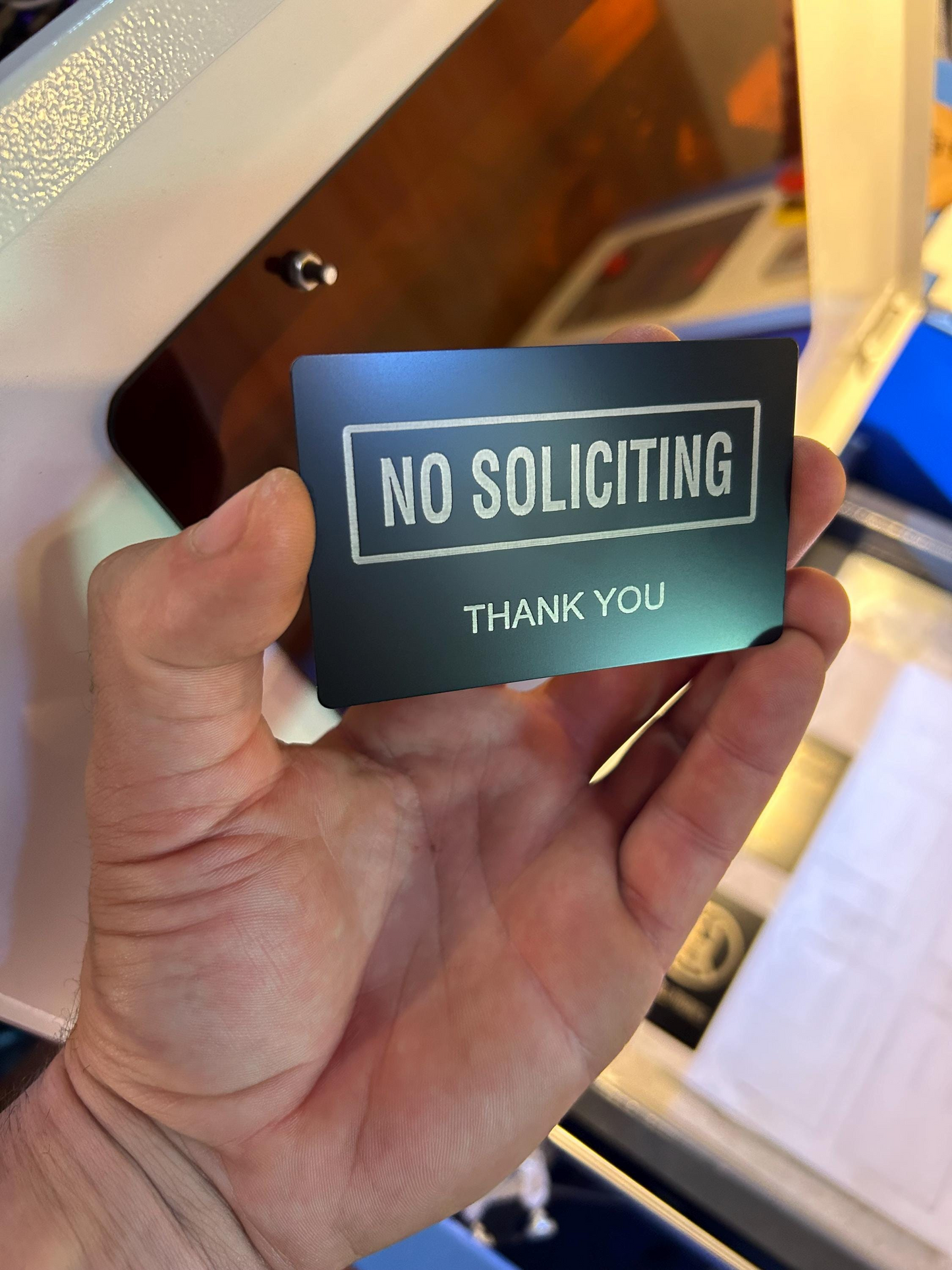 Hand showcasing custom anodized aluminum sign card engraved with “No Soliciting” for home or business