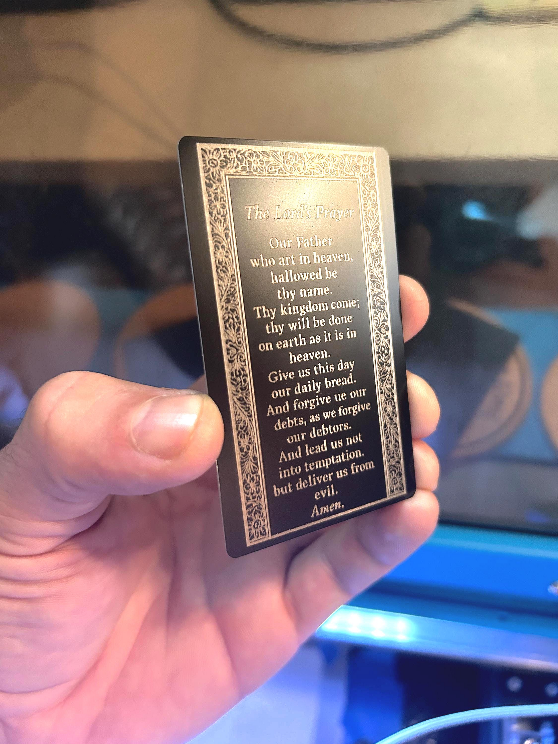 Close-up of laser engraved metal Christian keepsake card – The Lord’s Prayer text in silver on black