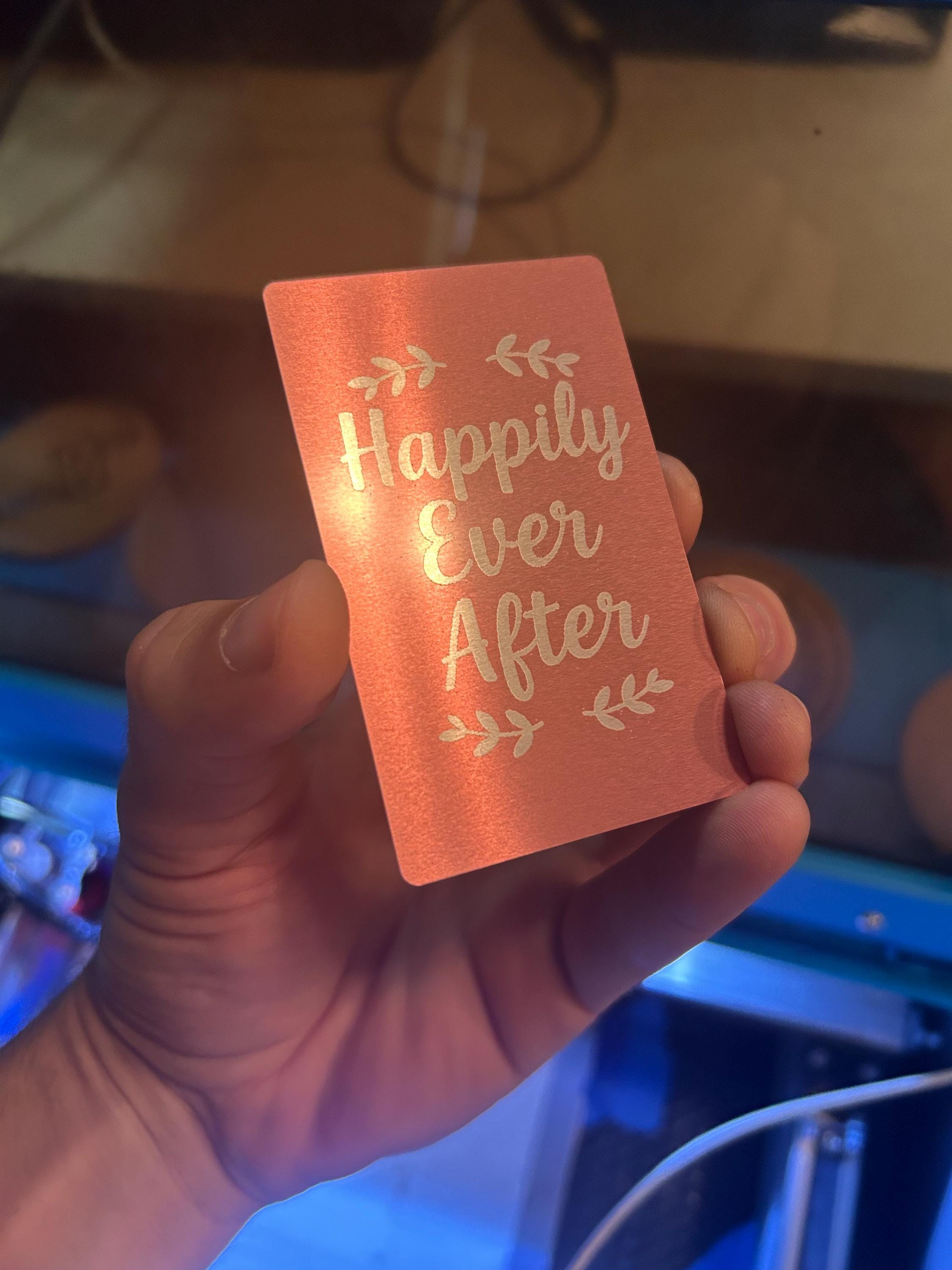Detailed shot of engraved anodized aluminum keepsake card – romantic “Happily Ever After” message in typography art in rose gold/silver finish