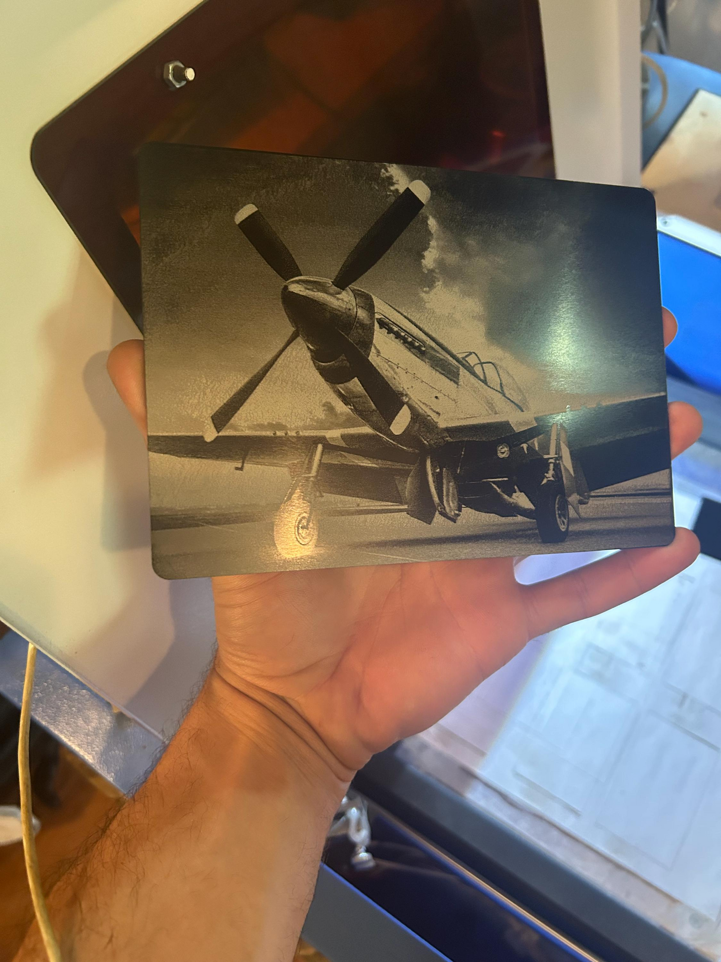 Hand holding a vintage photograph of an airplane laser engraved on to anodized aluminum placard