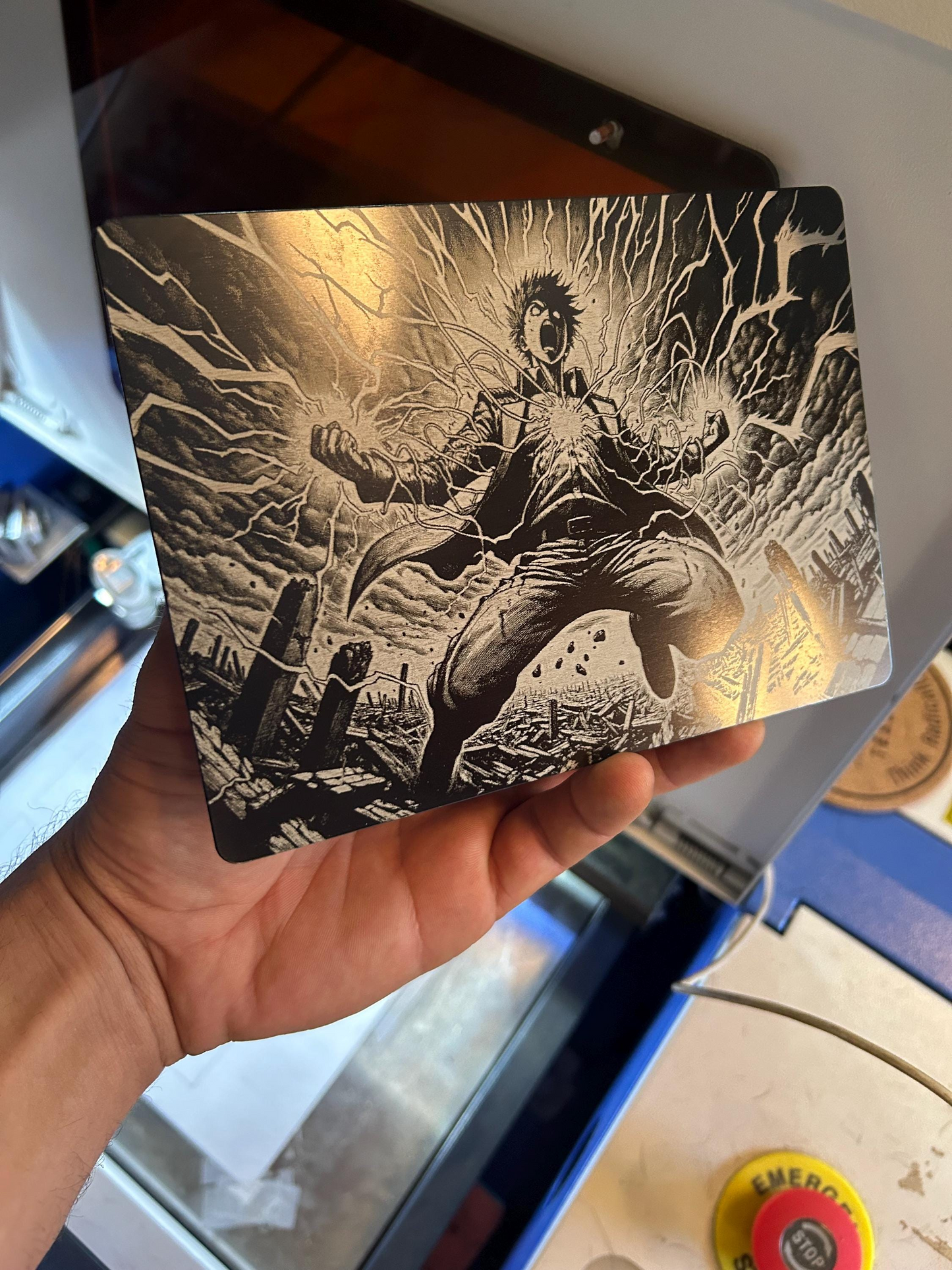 Hand holding a laser engraved plaque with black and white manga line art illustration of a battle character in a dynamic pose.