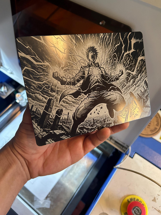 Hand holding a laser engraved plaque with black and white manga line art illustration of a battle character in a dynamic pose.