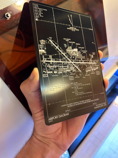 Hand holding a black and silver laser engraved airport approach plate engraving
