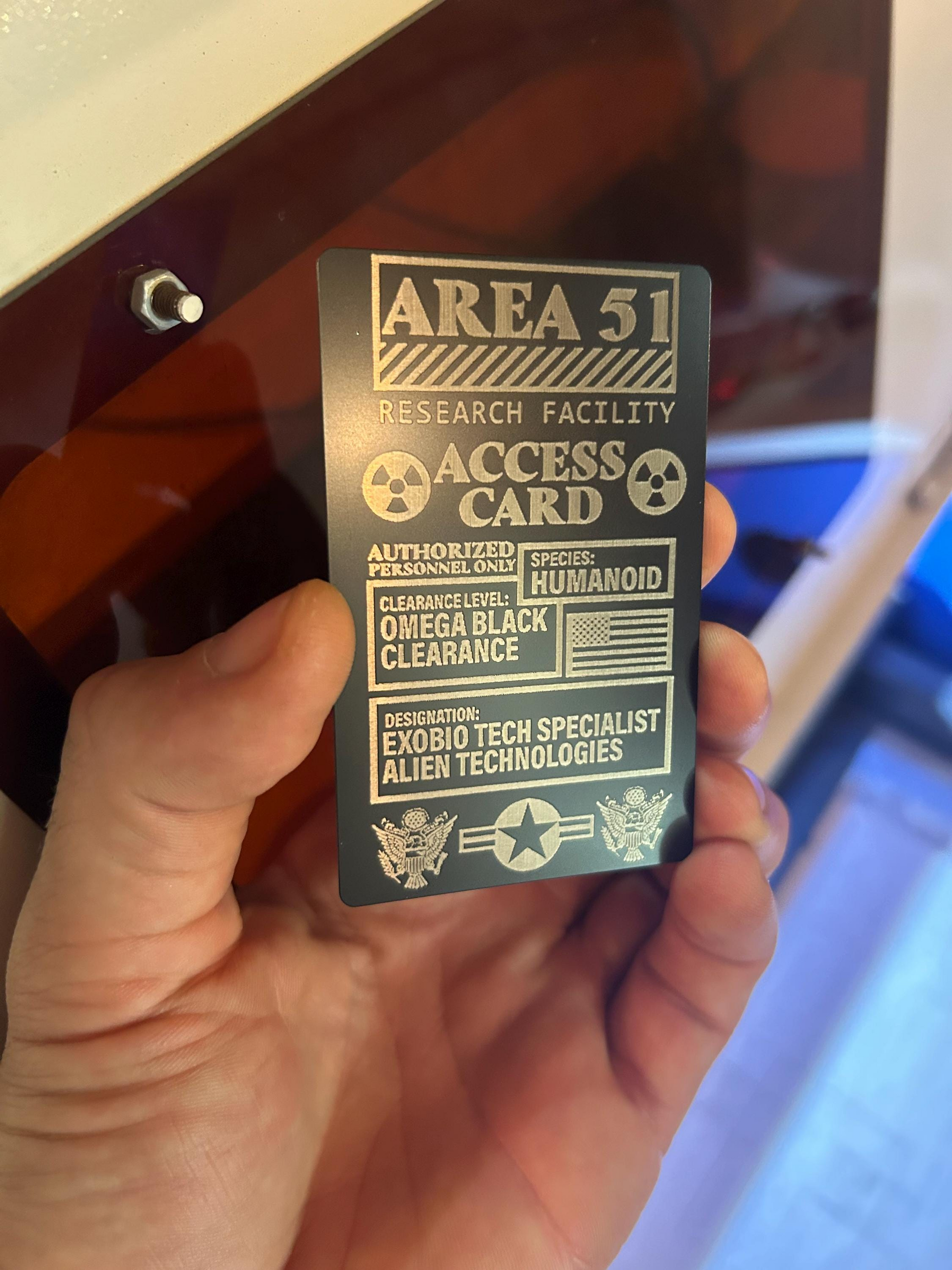 Hand holding an Area 51 access card with text and symbols.