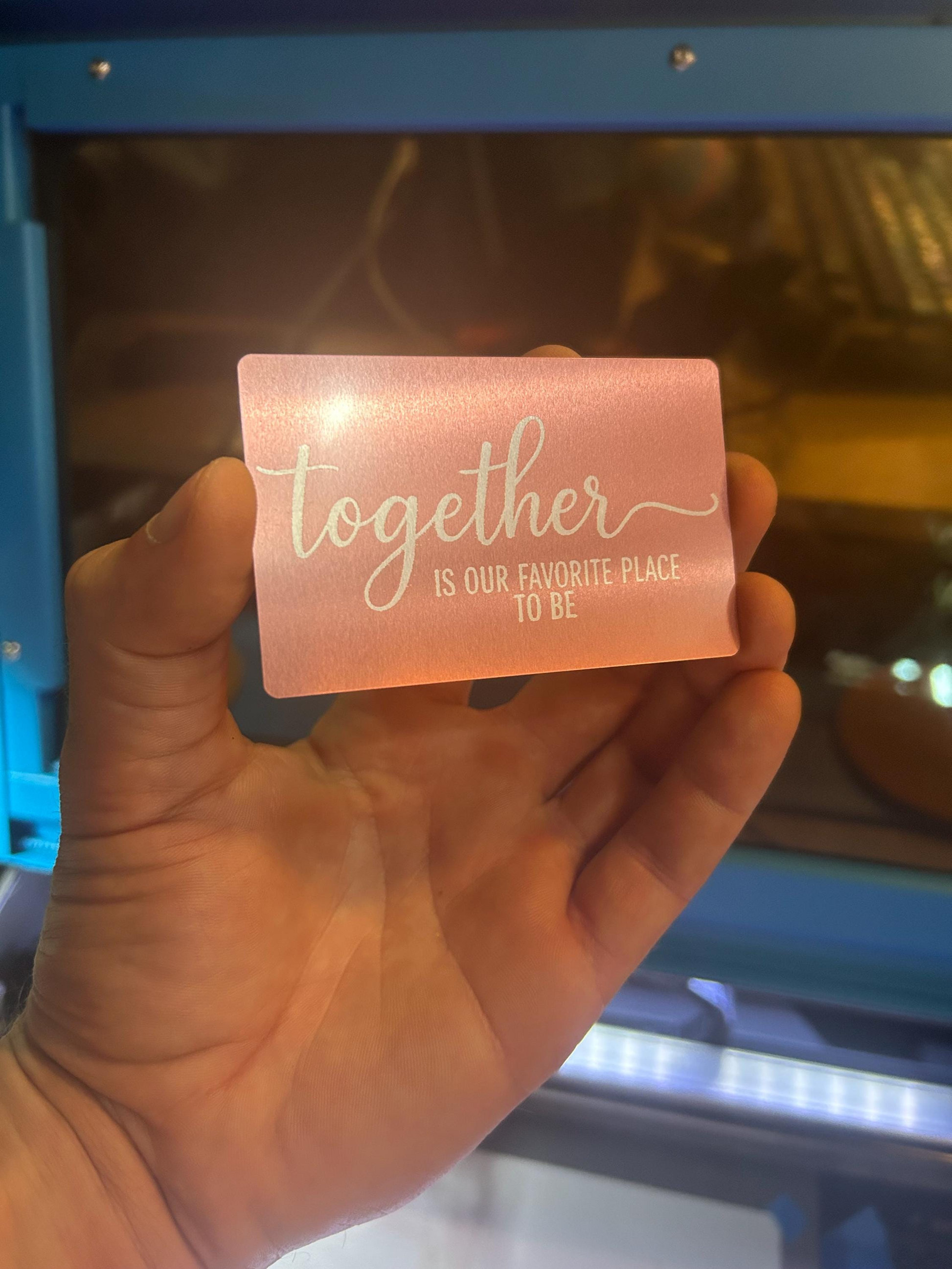 Person holding a romantic rose gold metal gift card with engraved “Together Is Our Favorite Place To Be” typography