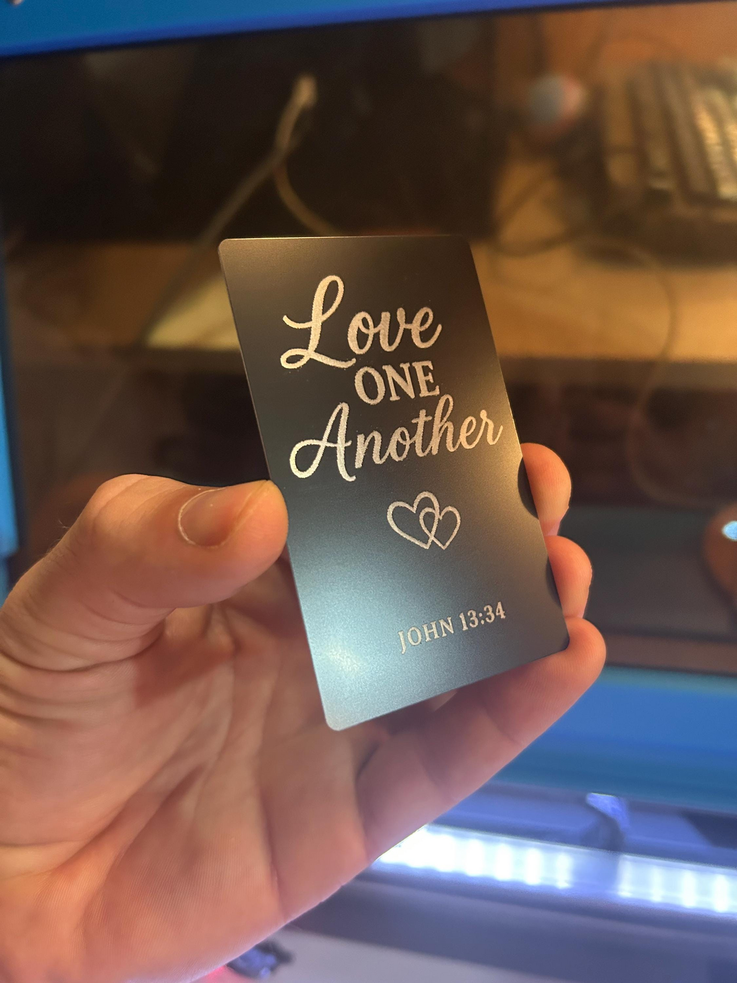 Angled shot of engraved anodized aluminum Bible verse plaque – “Love One Another” scripture gift