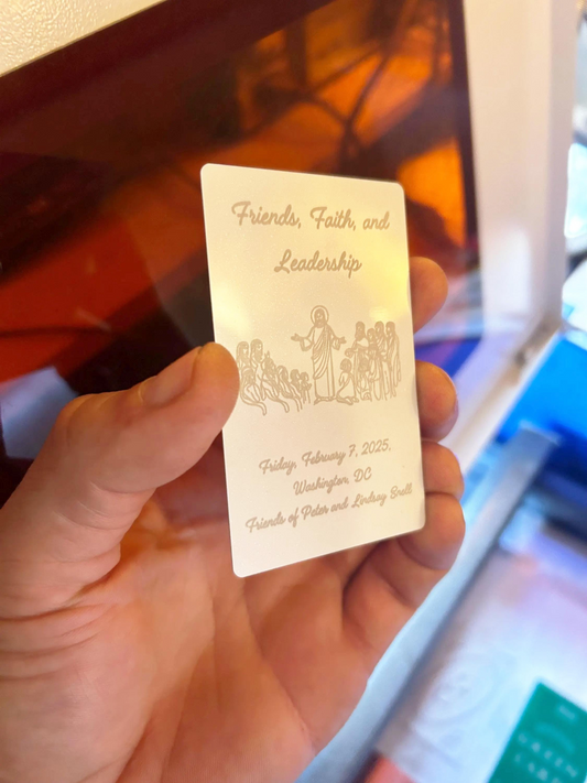 Hand holding a white/silver metal business card with custom event ticketing design with event name, date and logo