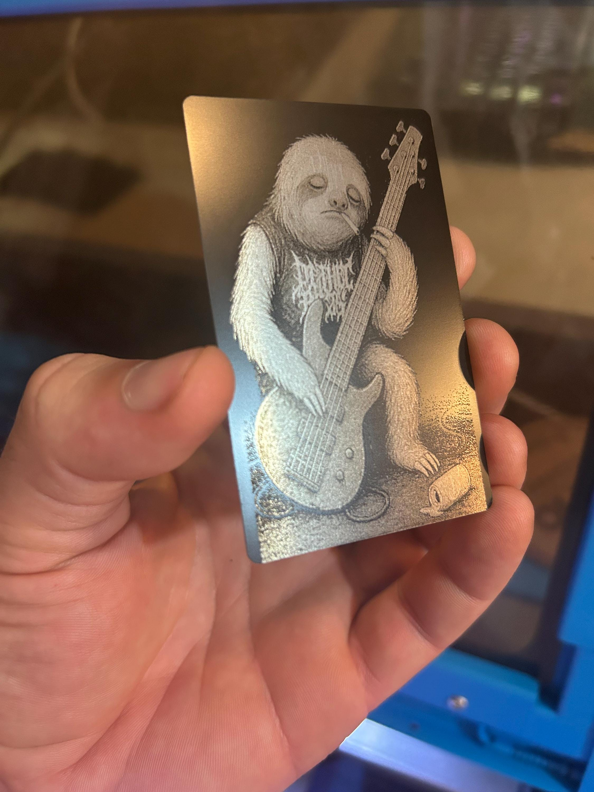 Hand holding a metal gag gift musician keepsake card, with a detailed design of a heavy metal themed sloth playing a guitar.