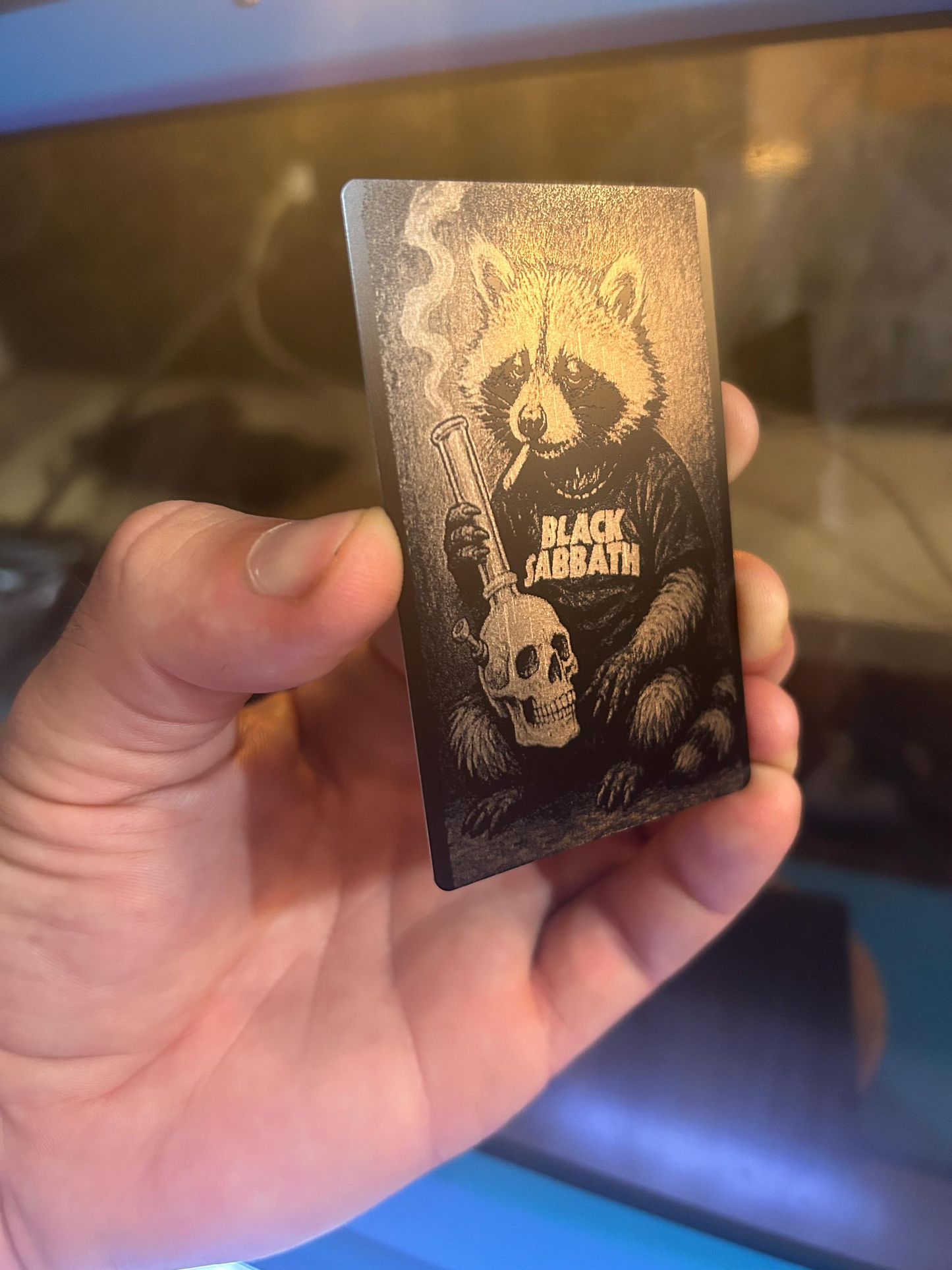 Hand holding a heavy metal raccoon cute animal rocker card with a bear and skull design.
