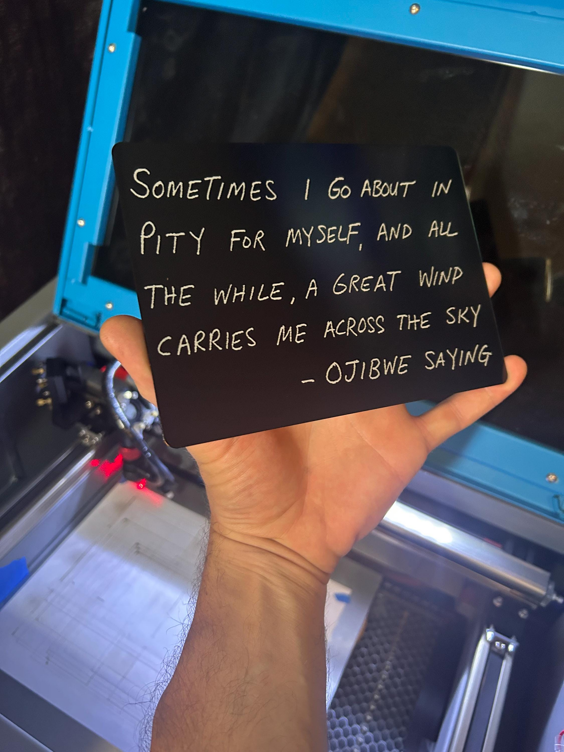 Hand holding a black metal sign with inspirational thought provoking pop culture quote  