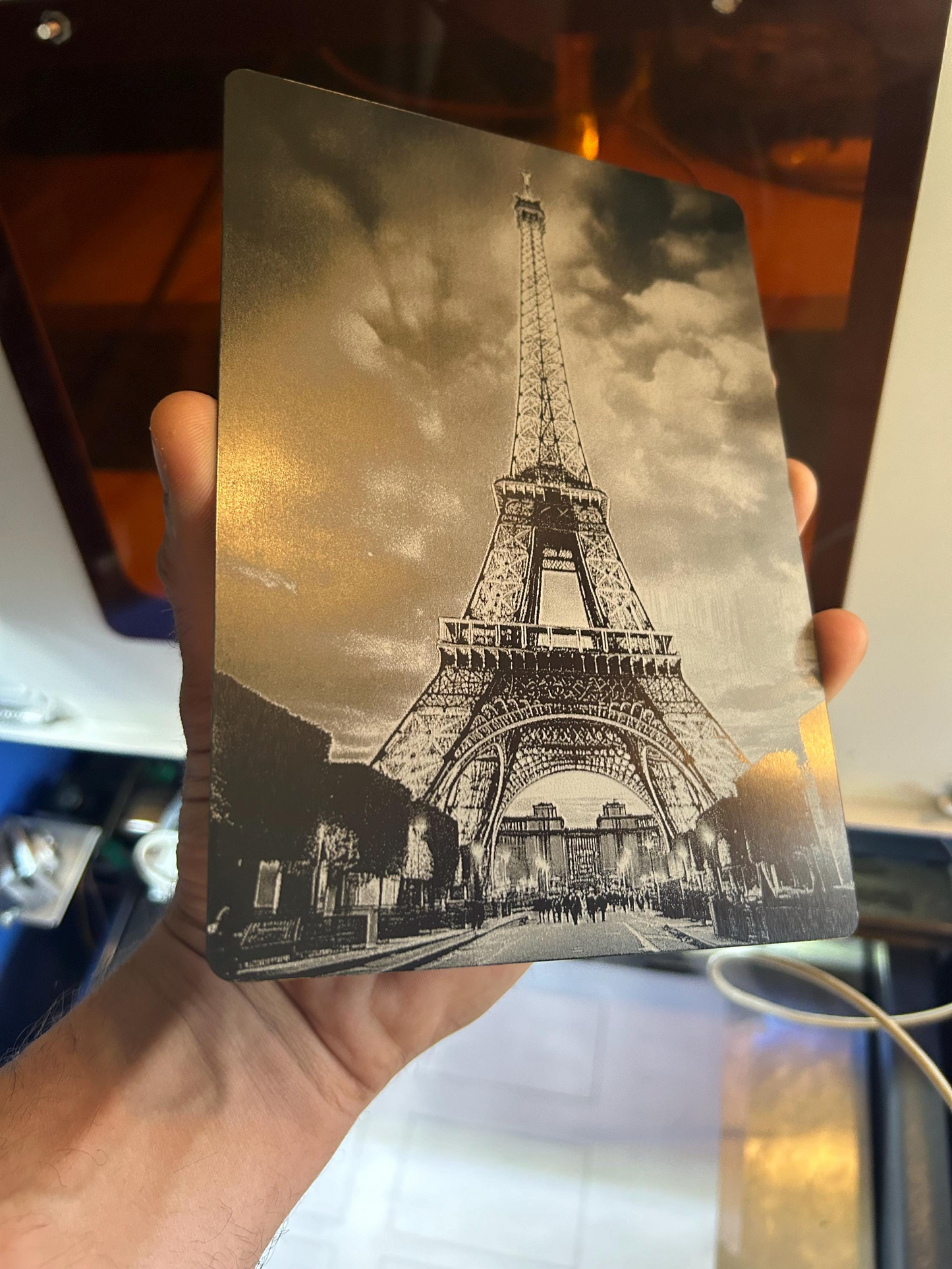 Vintage-style metal engraveing of the Eiffel Tower held by a person in 5x7 anodized aluminum