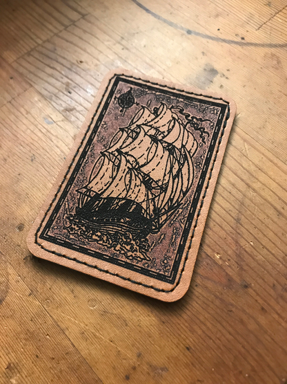Leather patch with a sail ship design on a wooden surface