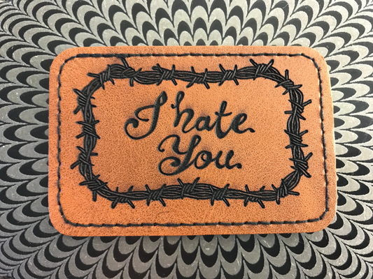 Brown leather Patch with 'I Hate You' text and barbed wire design on a patterned background