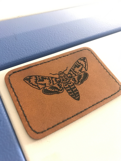 Brown leather patch with Cicada design on a blue and white background