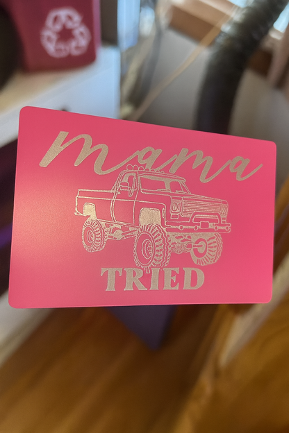 Rose gold card with a graphic of a truck and 'mama tried' text on a wooden surface.