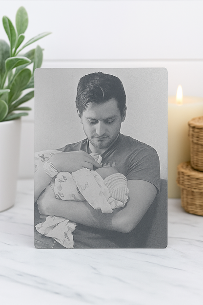 Decorative plaque with engraving of Man holding a baby with a plant and candle in the background