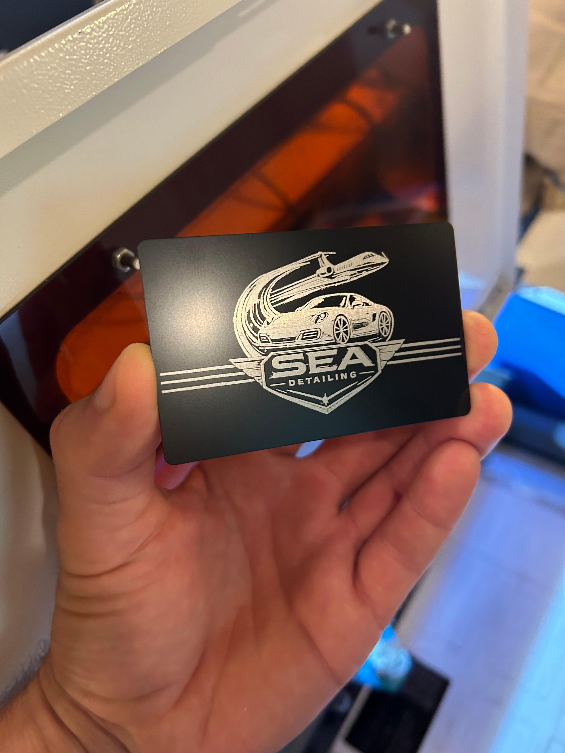 Laser engraved metal business card for auto detailing shop with logo and branding in black/silver