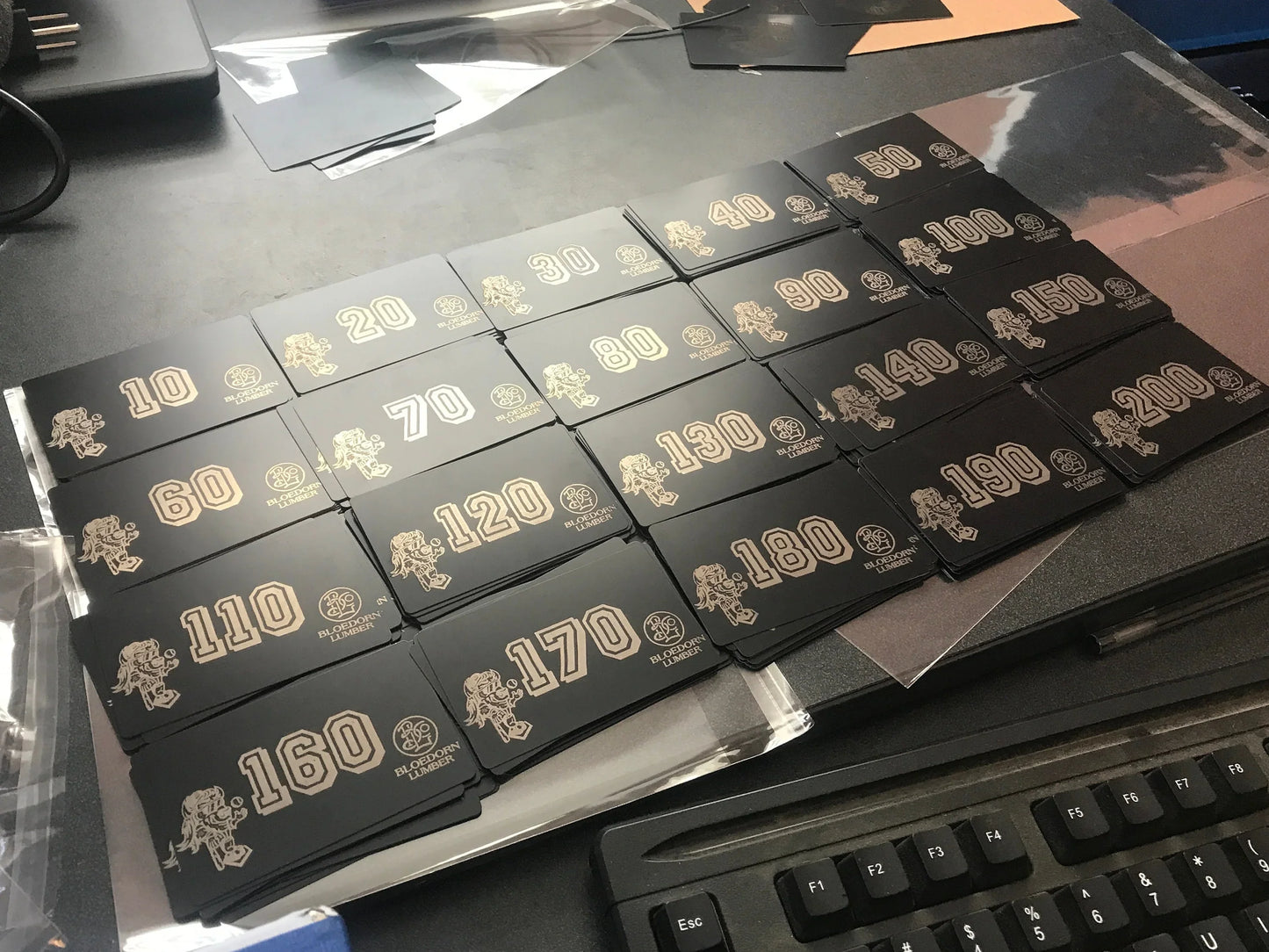 Stacks of bulk laser engraved metal business cards with custom text and design, pictured on a work desk