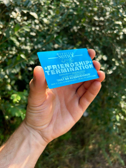 laser engraved friendship termination gag gift card product demonstration, blue/silver color metal keepsake in  an outdoor setting