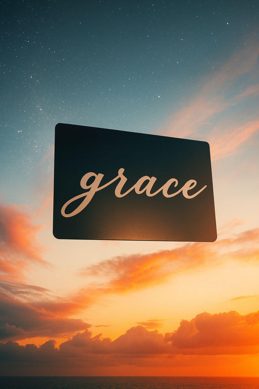 Metal wallet insert placard with 'grace' calligraphy text against a sunset sky