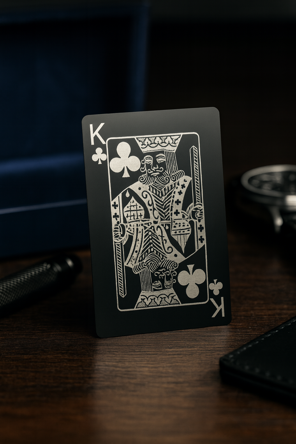 Black and silver metal playing card with a king of clubs laser engraved design on a wooden surface