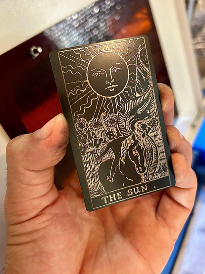 Laser engraved metal tarot card with The Sun artwork in black/silver anodized aluminum