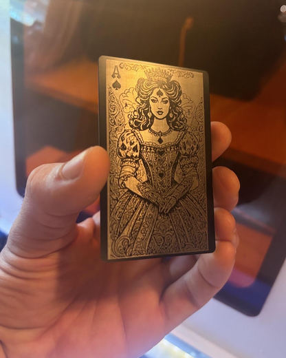 Metal black and silver playing card with a decorative Lady Luck Ace of SPades design held in a hand against a blurred background