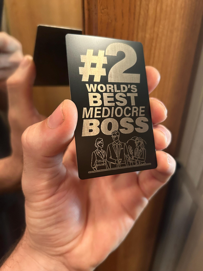 Card with '#2 World's Best Mediocre Boss' text held in a hand.