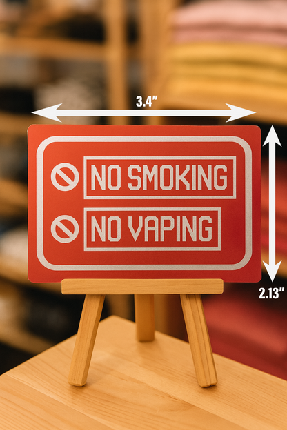 Red 'No Smoking, No Vaping' sign on a wooden stand with measurements indicated.