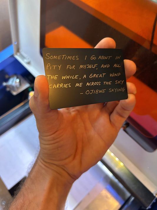 Laser engraved metal ojibwe saying card "Sometimes I go about in pity for myself" text in black/silver