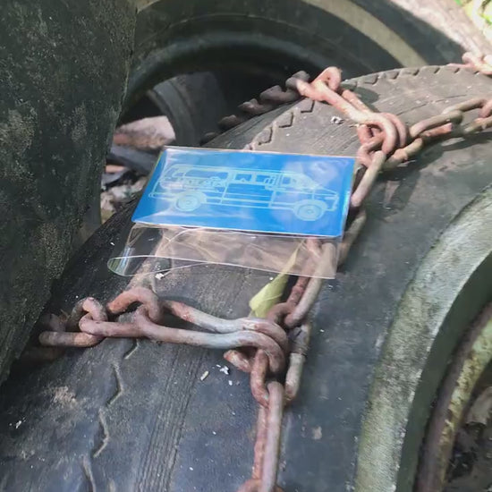 a blue/silver metal business card in cellophane packaing, shown on top of tires and chains
