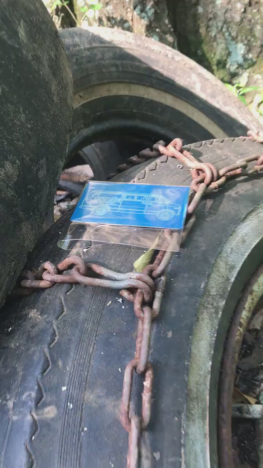 a blue/silver metal business card in cellophane packaing, shown on top of tires and chains