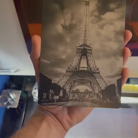 Close-up video of black anodized metal 5x7 plaque rotating to show laser engraved Eiffel tower artwork